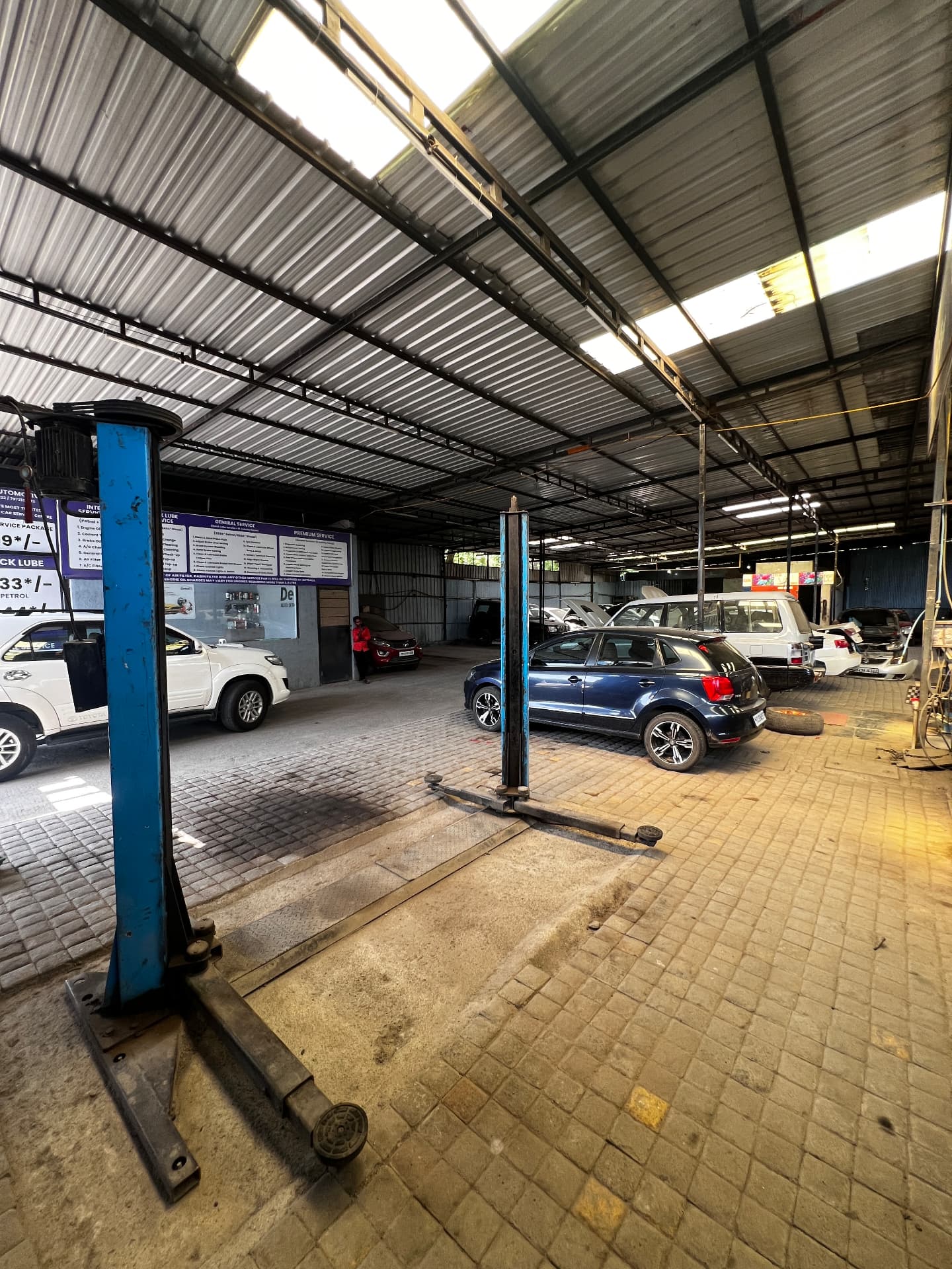 Two-post hydraulic lifts and service bays inside the Pune Automotive workshop in Pune