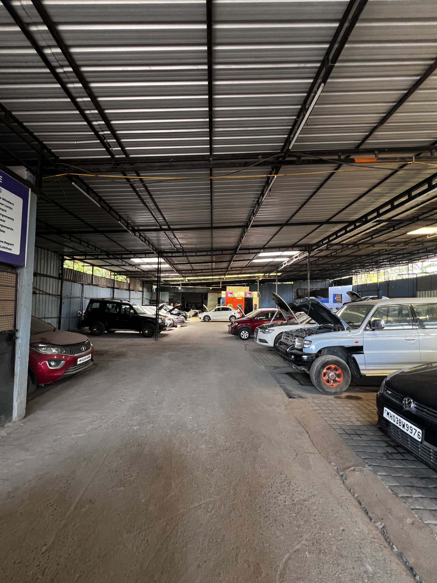 Bodyshop area of Pune Automotive with SUVs and hatchbacks parked for repair work